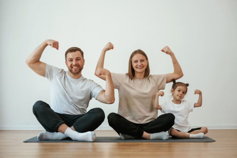 showing-biceps-strong-family-mother-father-daughter-are-doing-yoga-home
